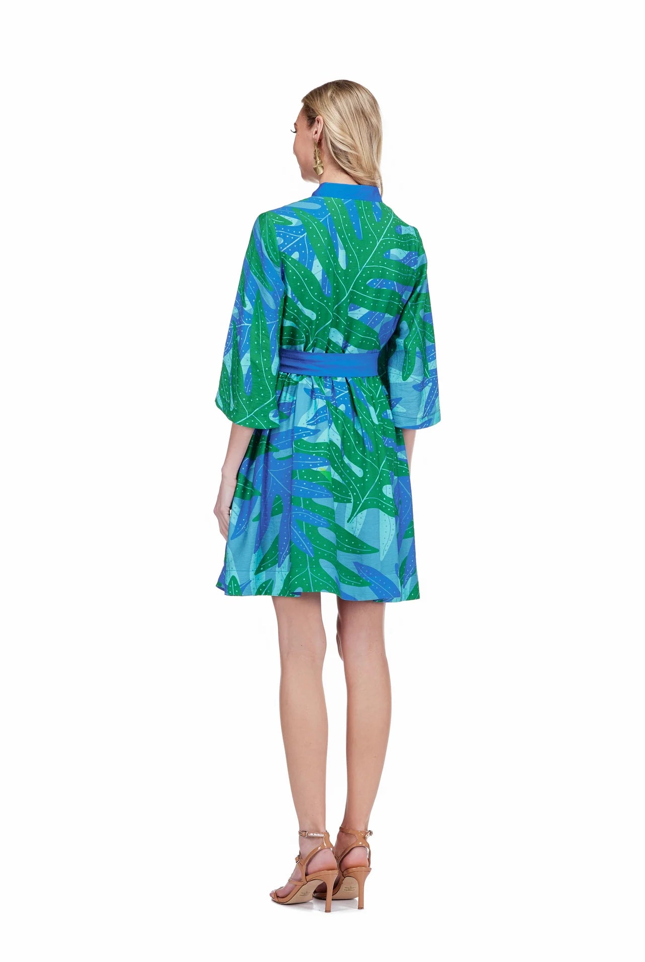 Woman wearing a green and blue leaf-patterned dress on a white background