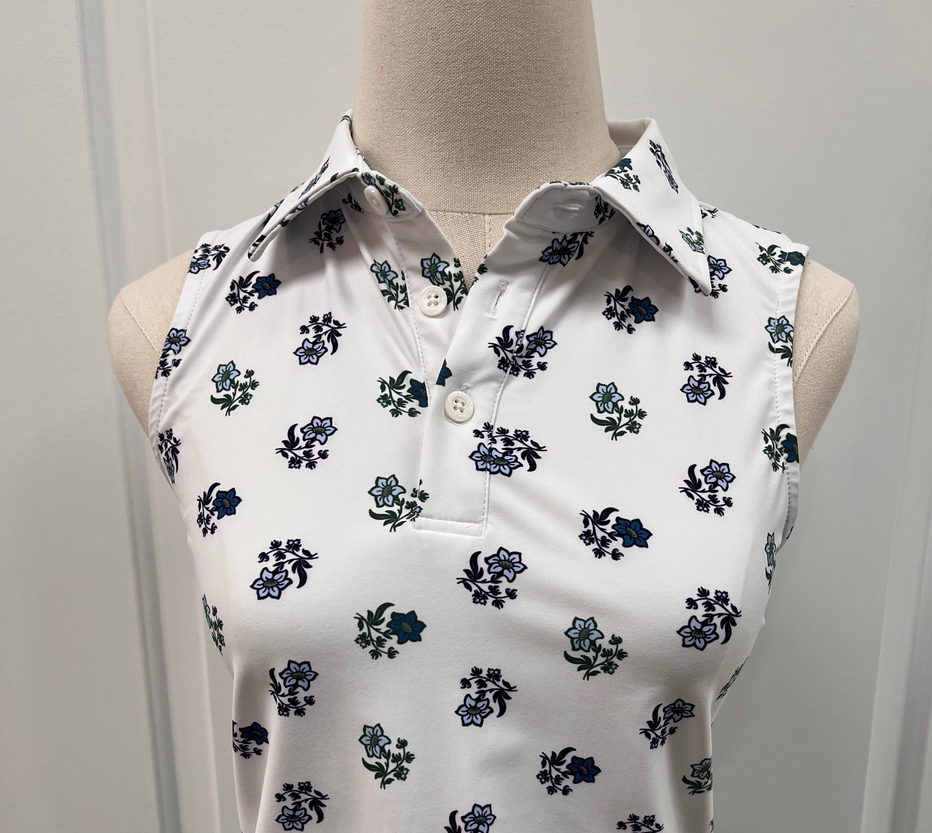 White sleeveless collared top with a navy and green floral print, displayed Style#12076