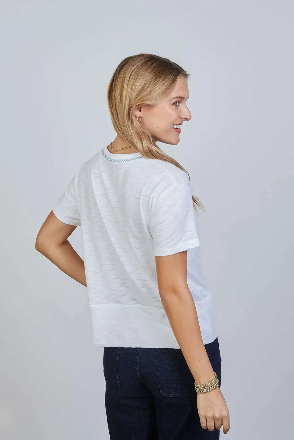 Side view of Erin Gray Charli Tee in white with blue stitching, a stylish casual top with contrast stitching details.
