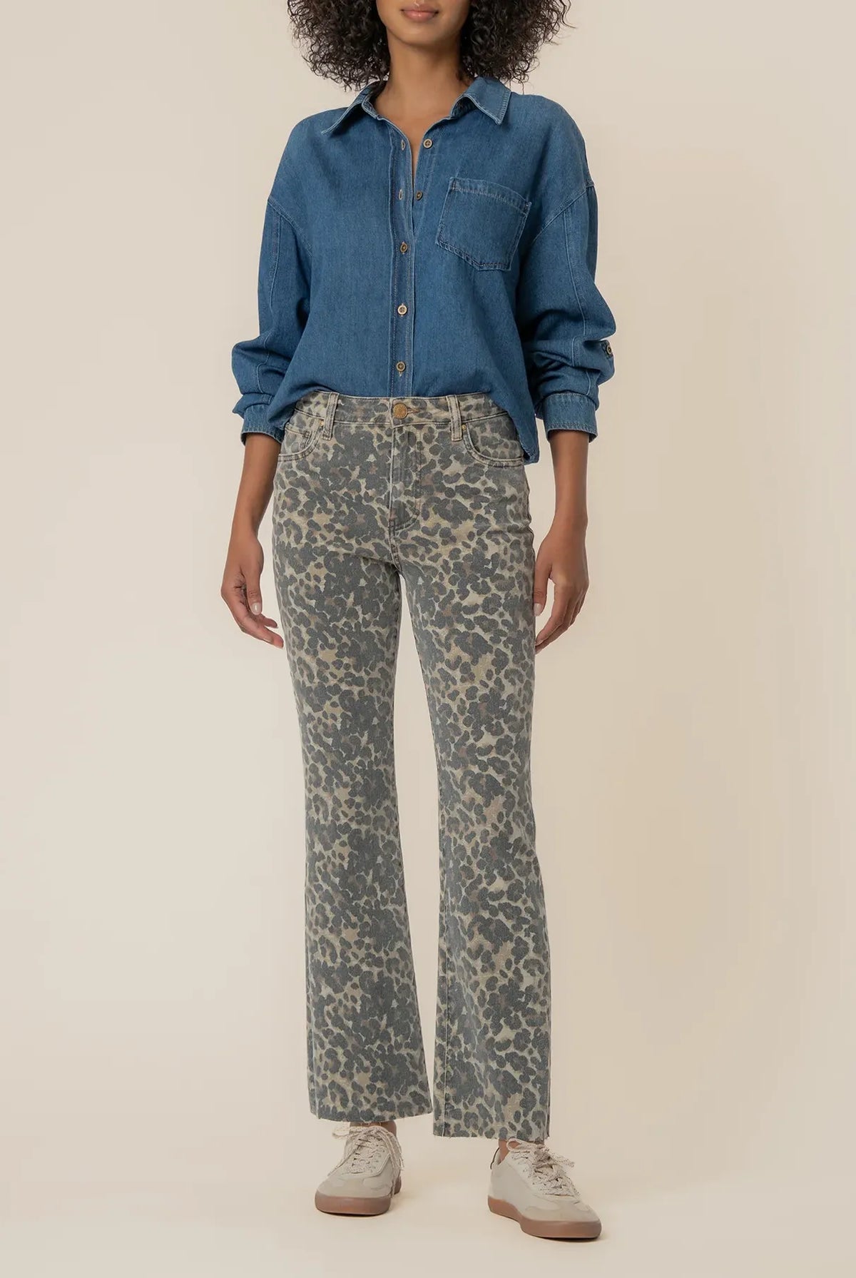 Person wearing a blue denim shirt and patterned pants on a beige background