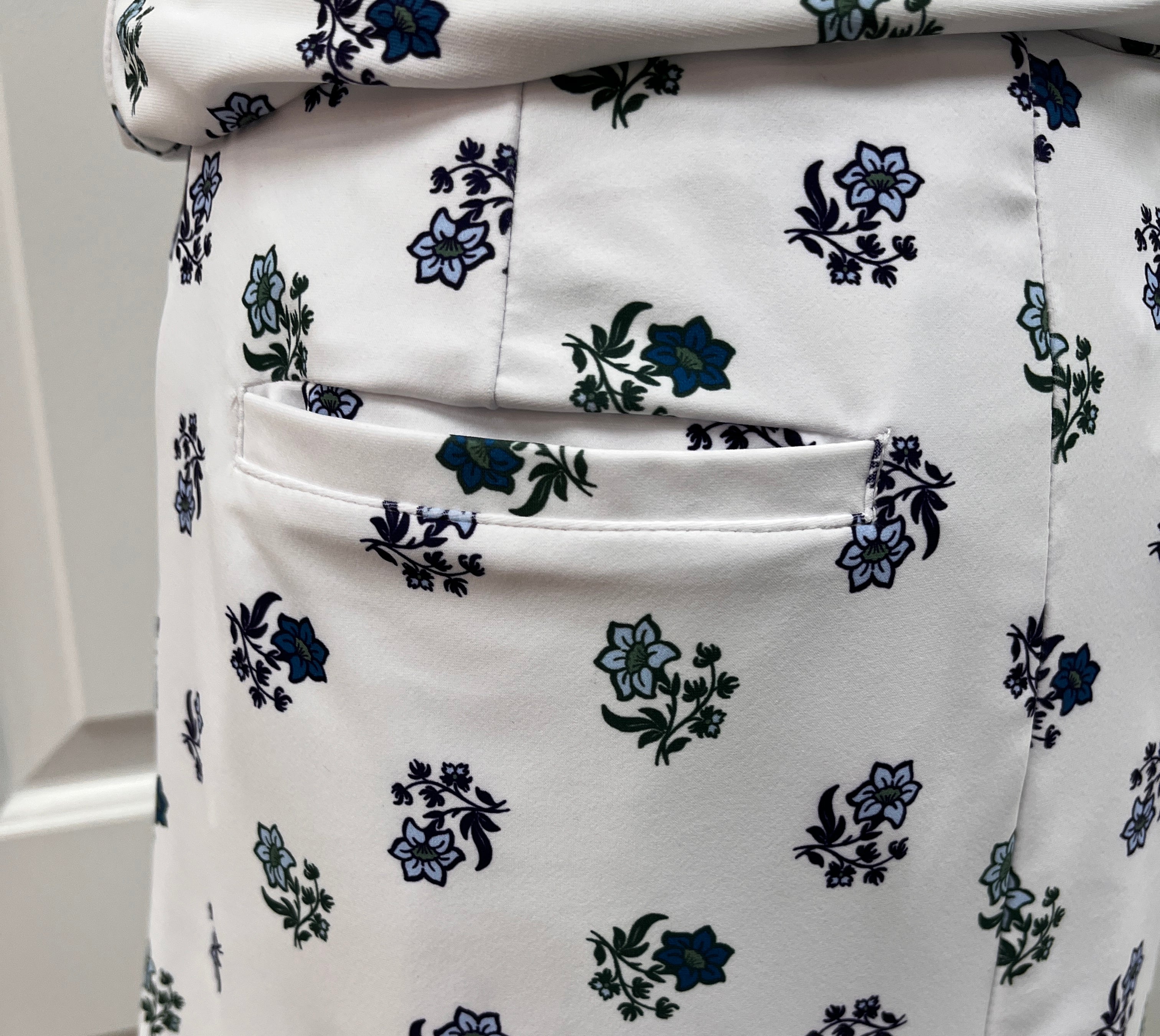 Close-up of a white skirt with a small-scale floral print in navy blue and green, featuring a side pocket.