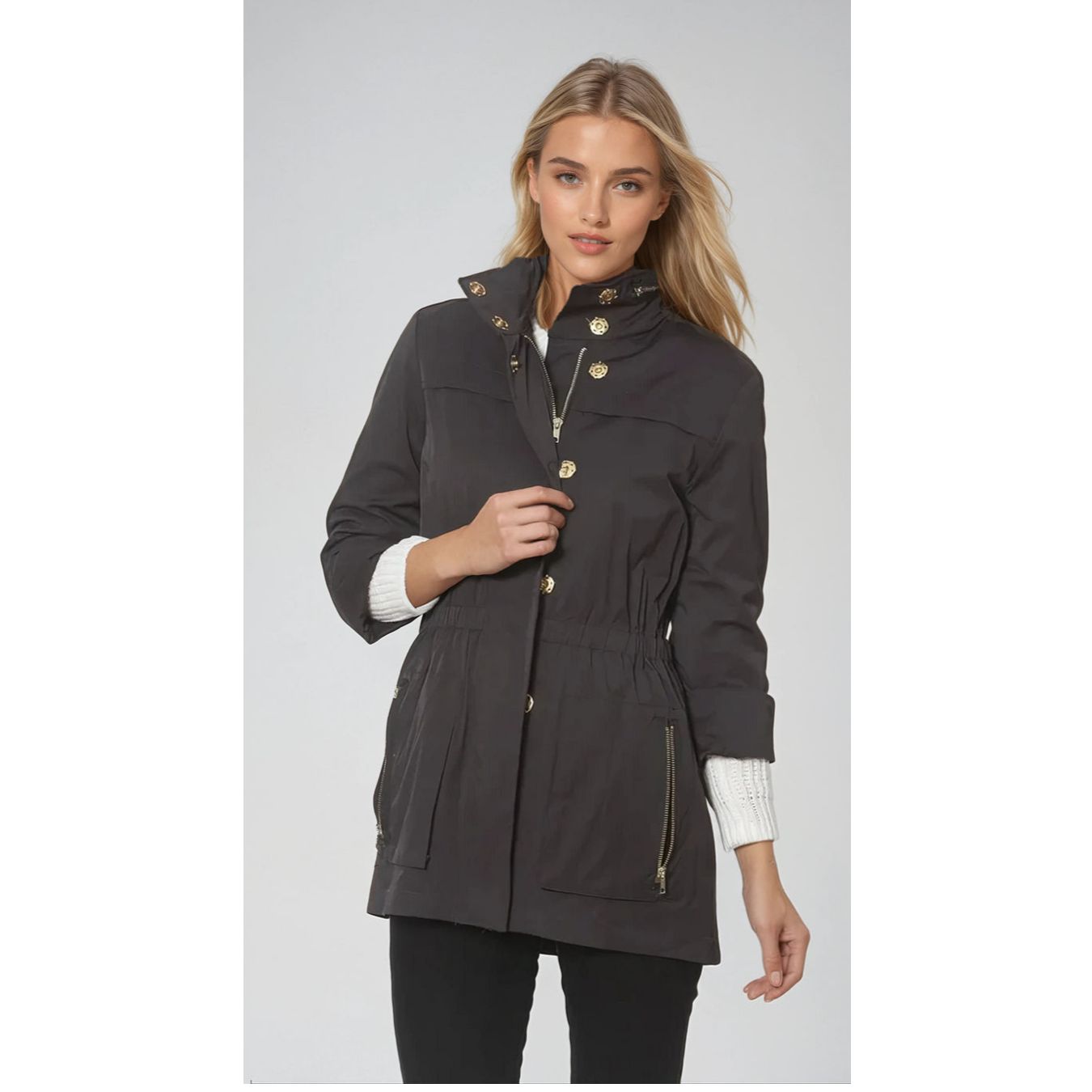Woman wearing a dark gray parka with gold buttons on a light gray background