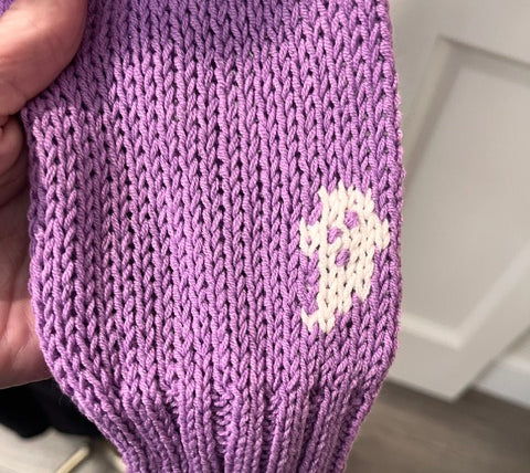 Wooden Ships Mini Ghost Sweater in purple, style K57CE2W739 — close-up of knit ghost motif on ribbed cuff and sleeve