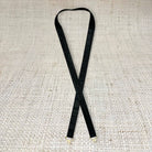 Black skinny leather belt from Garland Bags, close-up view showing sleek design and smooth leather strap.
