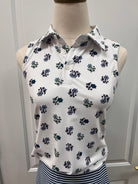 White sleeveless collared top with a navy and green floral print, displayed on a beige dress form mannequin against a white paneled door background.