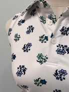 Close-up of a white top with a repeating floral print in blue and green, featuring a buttoned neckline.