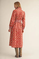 long-sleeve red midi dress with a white geometric pattern and a matching waist tie