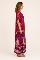 Briton Court Diana Maxi Dress in Sunset Swans print, full-length maxi silhouette with swan border hem detail, side view