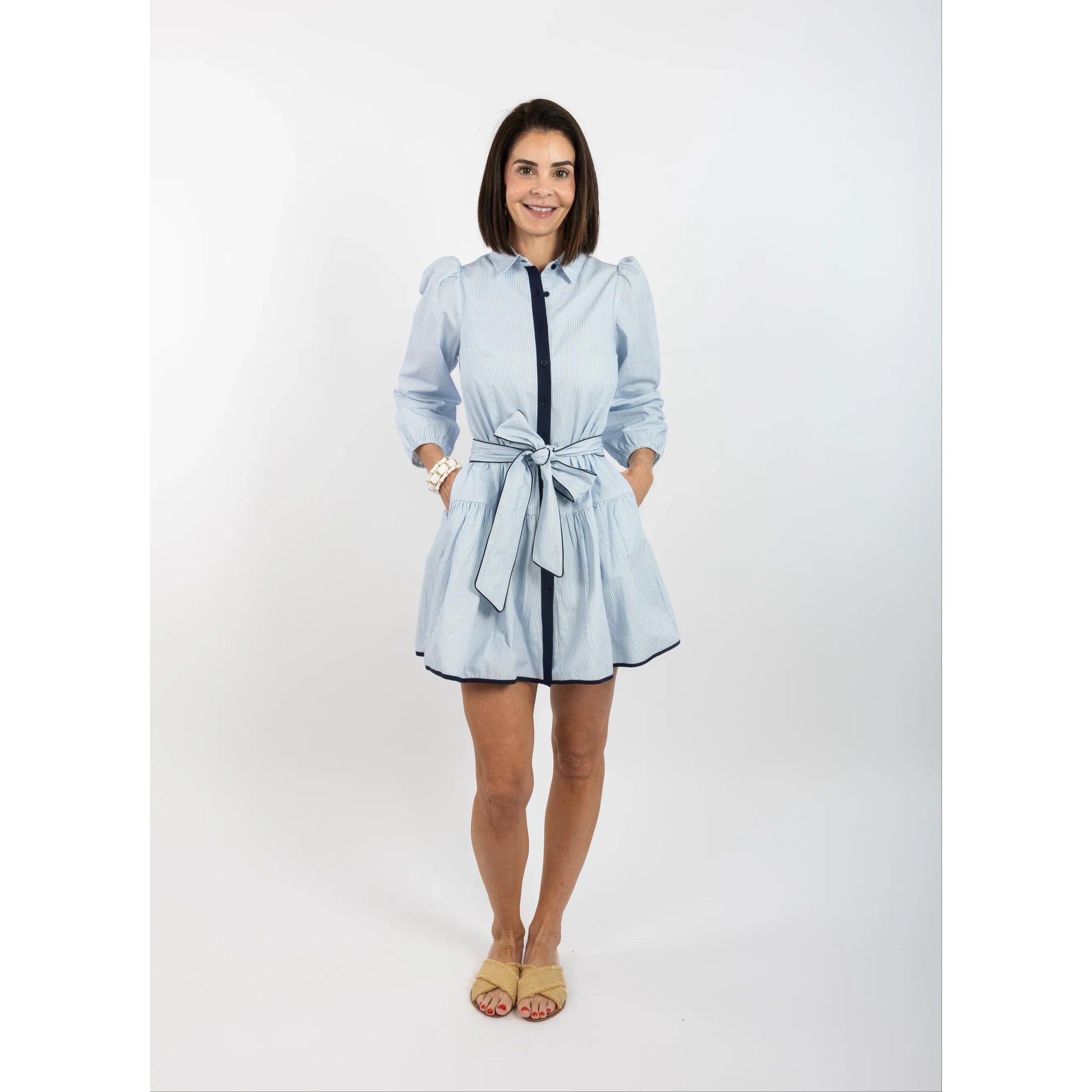 Woman wearing a light blue dress with a belt on a white background