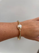 gold hinged cuff bracelet with a single white freshwater pearl,