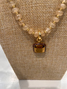 Harvest Pendant Beaded Necklace by Smith and Co. Design — close-up of square amber enamel pendant on cream glass bead strand