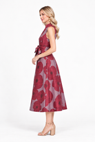 Clara Dress by Jade in crimson poppy, side view showing sleeveless bodice, waist sash, and midi skirt