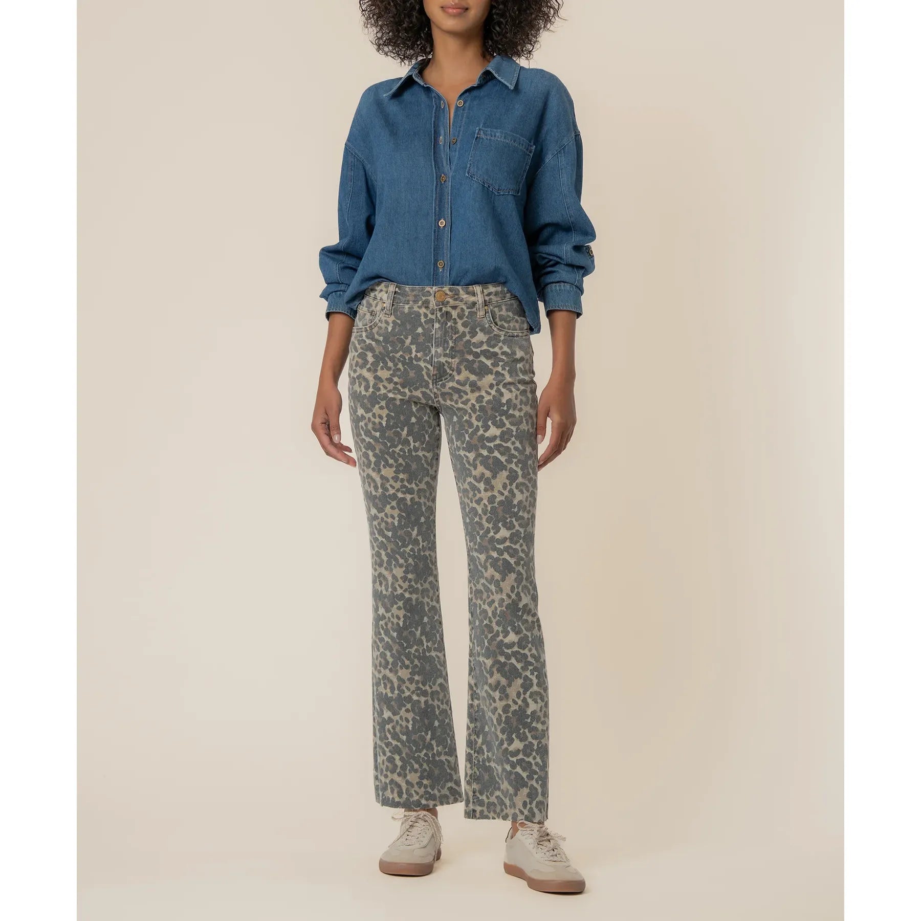 Person wearing a blue denim shirt and patterned pants on a beige background