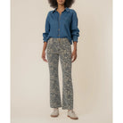 Person wearing a blue denim shirt and patterned pants on a beige background