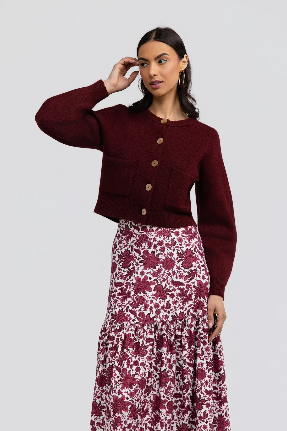 Hildy Sweater by Smith & Quinn in burgundy, showing cropped hem, button front, and balloon sleeves with one arm raised