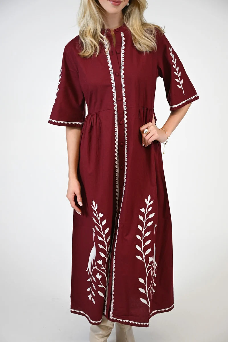 long maroon dress with white embroidered leaf patterns and white trim, 