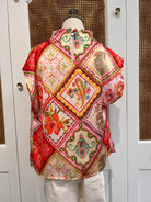 A multicolor patchwork-patterned fabric cover, likely for a garment or storage container, displayed on a white mannequin torso against a white cabinet background.