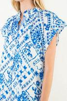 Suzie Dress by THML — close-up of split V-neck, button placket with striped lining, ruffle collar, cobalt blue tile print detail
