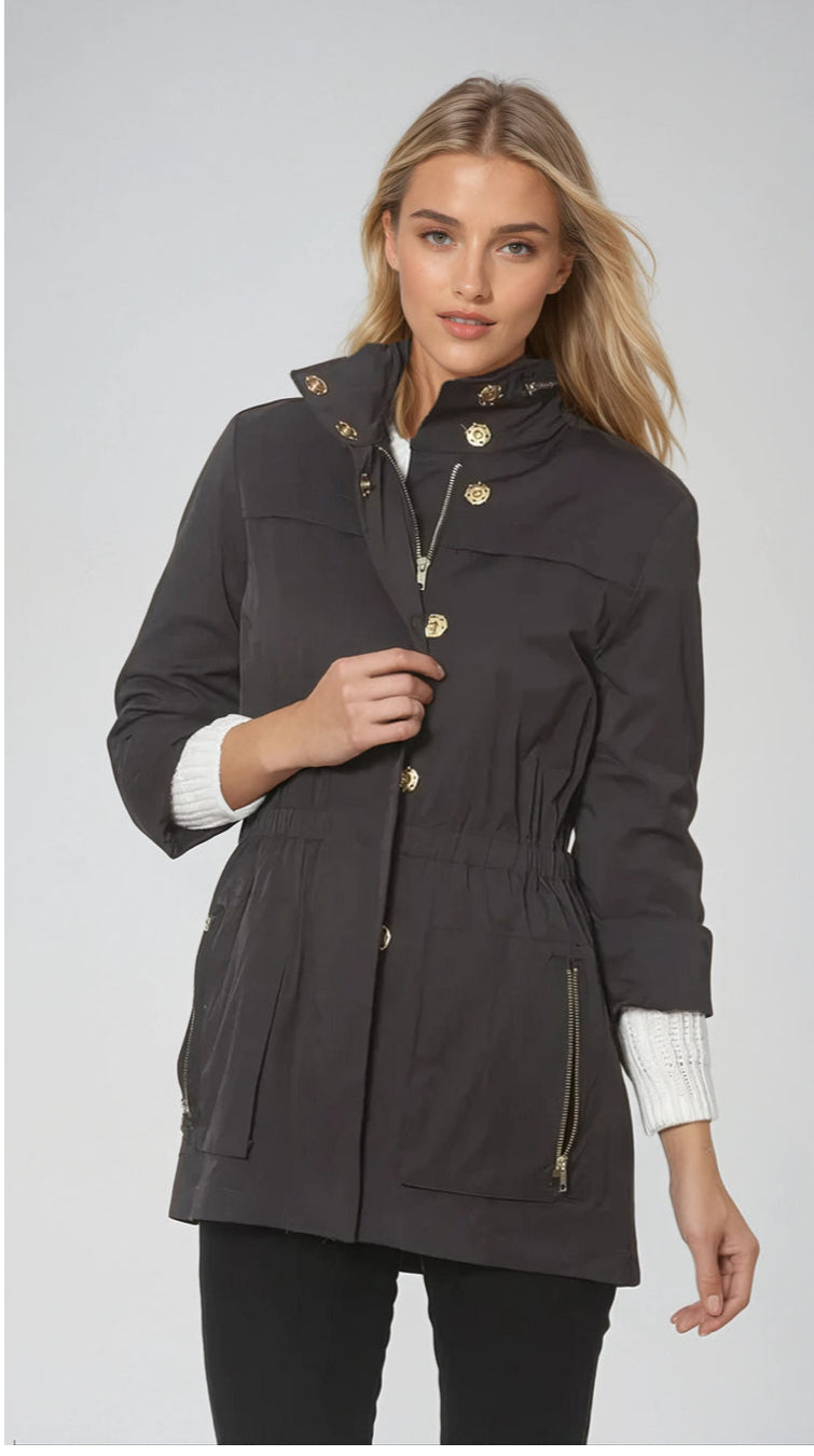 Woman wearing a dark gray parka with gold buttons on a light gray background