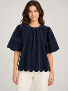 Greer Top by Voy in navy corduroy on a model, front view with gathered neckline, scalloped sleeve trim and scalloped hem