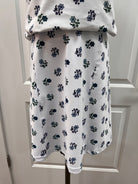 A white fabric curtain panel with a repeating navy blue floral pattern, hanging on a metal rod in front of a white paneled door.