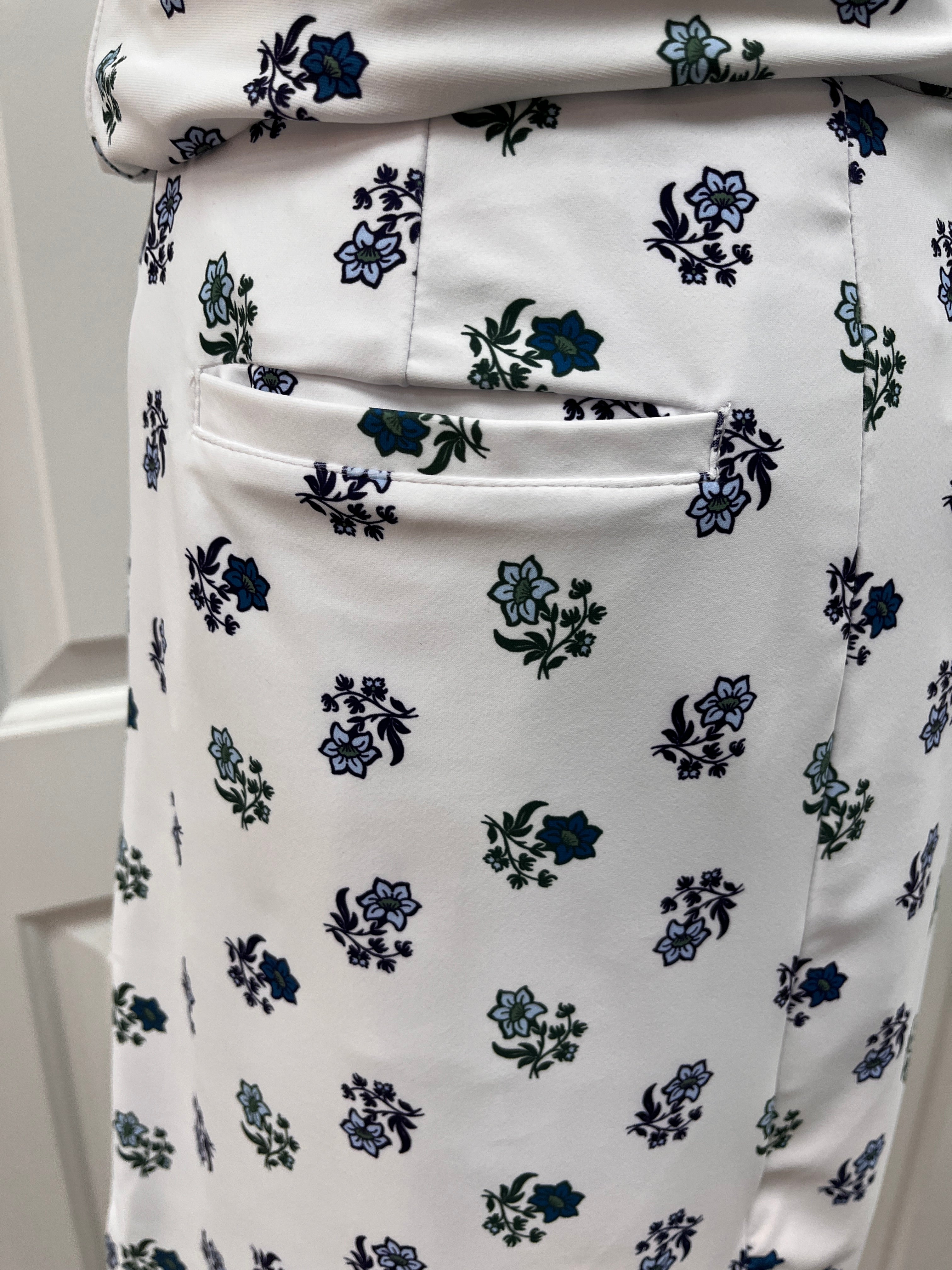 Close-up of a white skirt with a small-scale floral print in navy blue and green, featuring a side pocket.