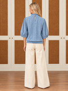 Alice Top by Voy in light blue textured knit with a smocked high neck, puff sleeves, and ruffled hem, back view
