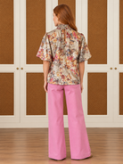 Evelyn Top by Voy with multicolor florals on a champagne shimmer background, smocked high neck, and puff sleeves, back view