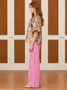 Evelyn Top by Voy with multicolor florals on a champagne shimmer background, smocked high neck, and puff sleeves, side view
