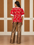 Sandra Top by Voy in red with a horse-and-lantern pattern, ivory neckline, puff sleeves, and scalloped hem, back view
